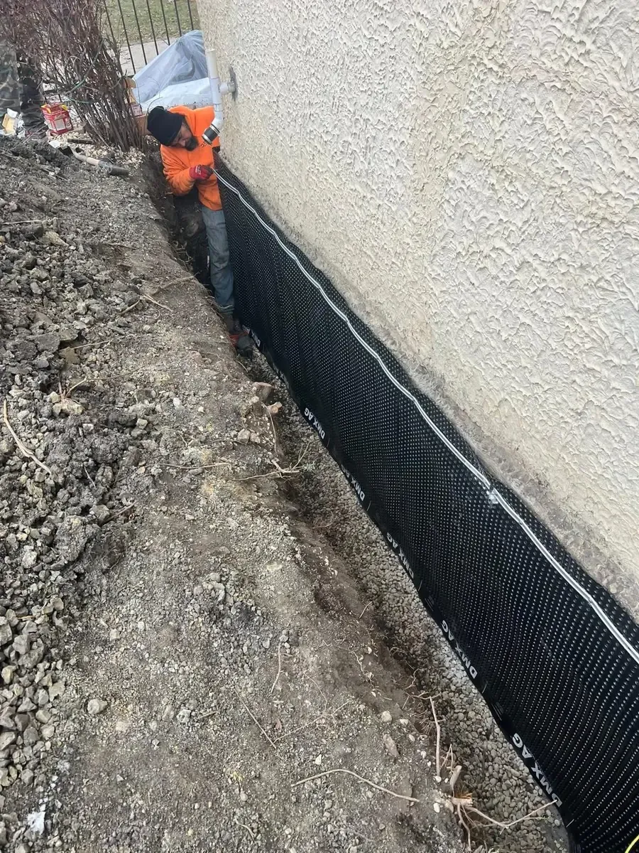 Waterproofing membrane being installed along an exposed foundation wall